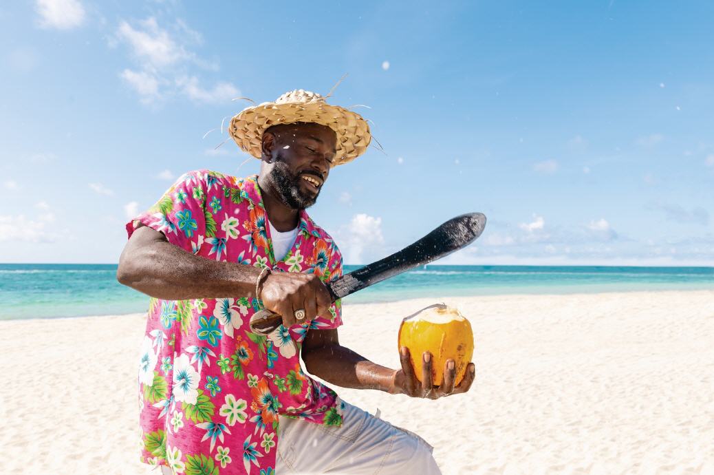Mann öffent am Strand Kokosnuss mit Machete
